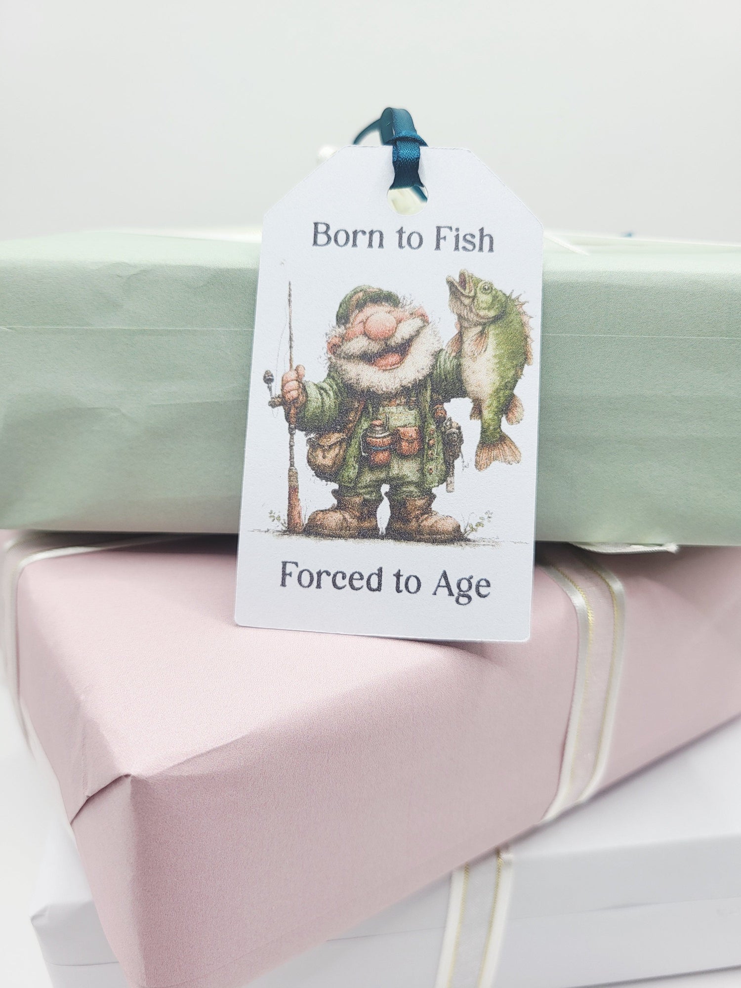 Rectangular gift tag with an old fisherman holding a fish in one hand and a rod in the other with the quote Born to Fish Forced to age