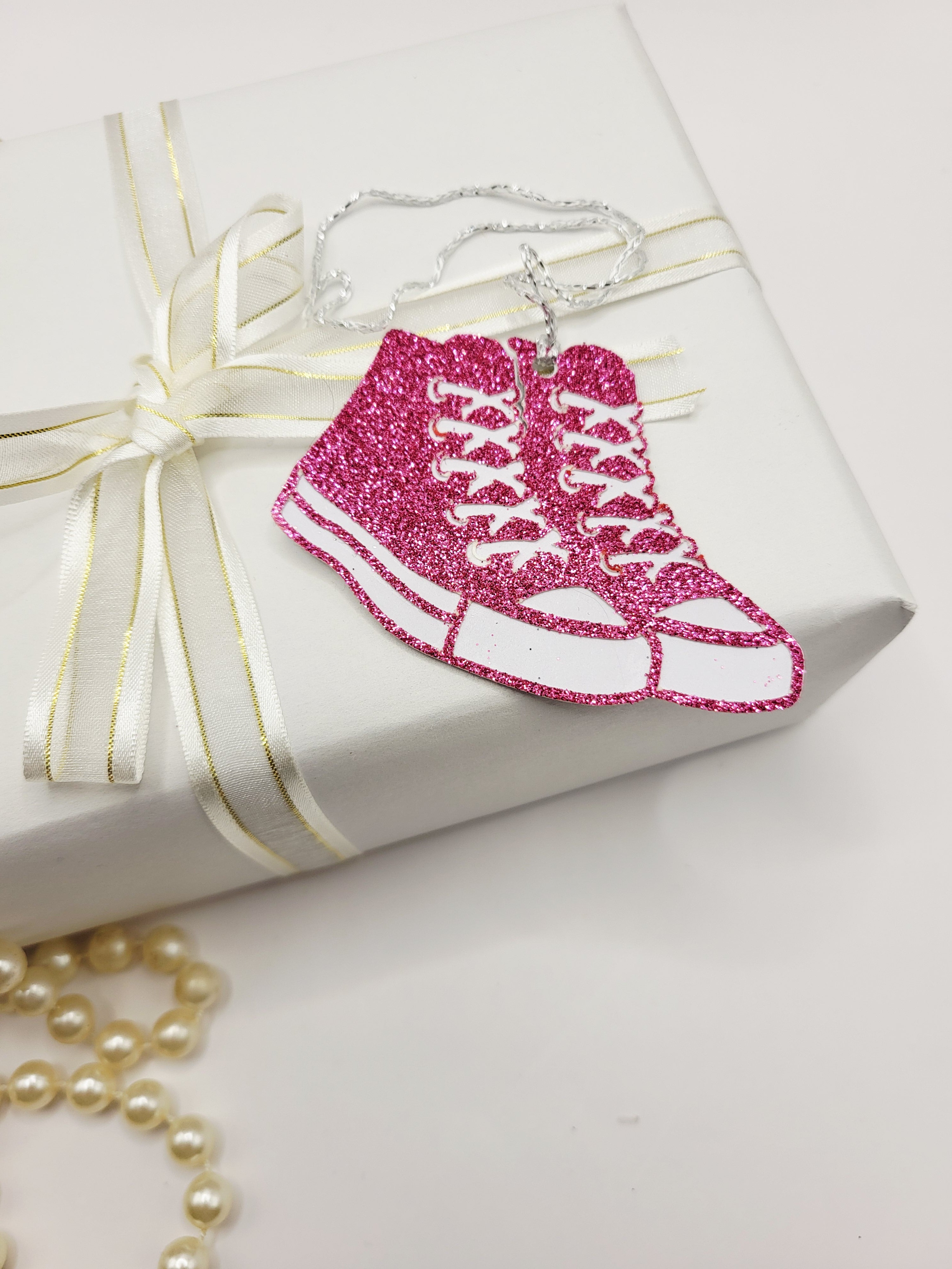 Pink glitter baseball boots with a white background. There is a silver metallic cord to attach to your gift
