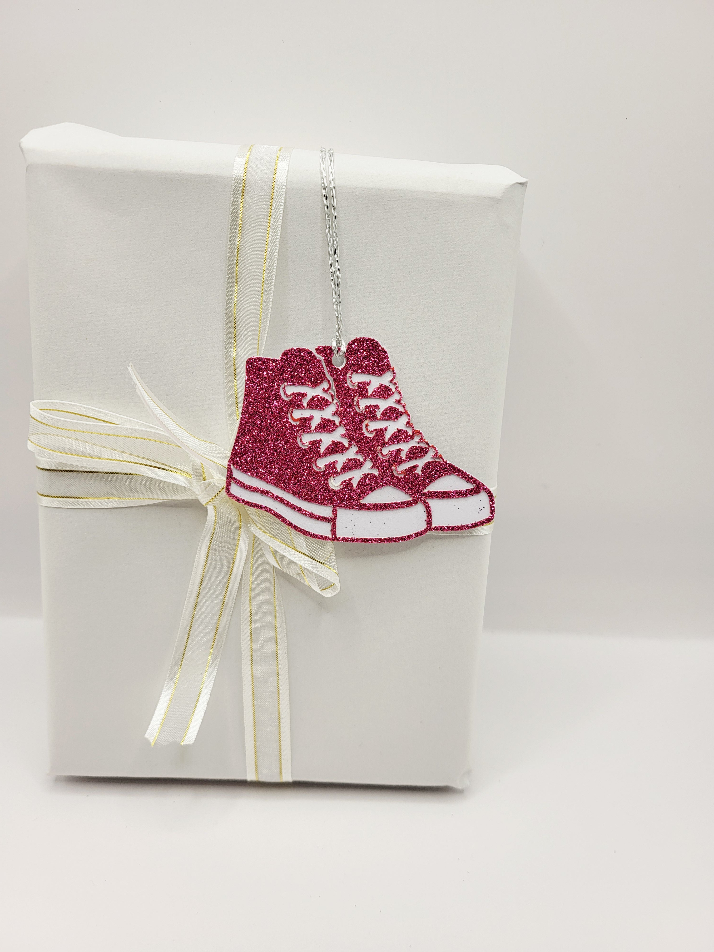 Pink glitter baseball boots with a white background. There is a silver metallic cord to attach to your gift