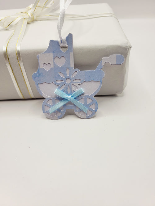 Pram shaped gift tag in blue gingham  on a white background. Pram has a blue bow and a white satin ribbon to attach the tag