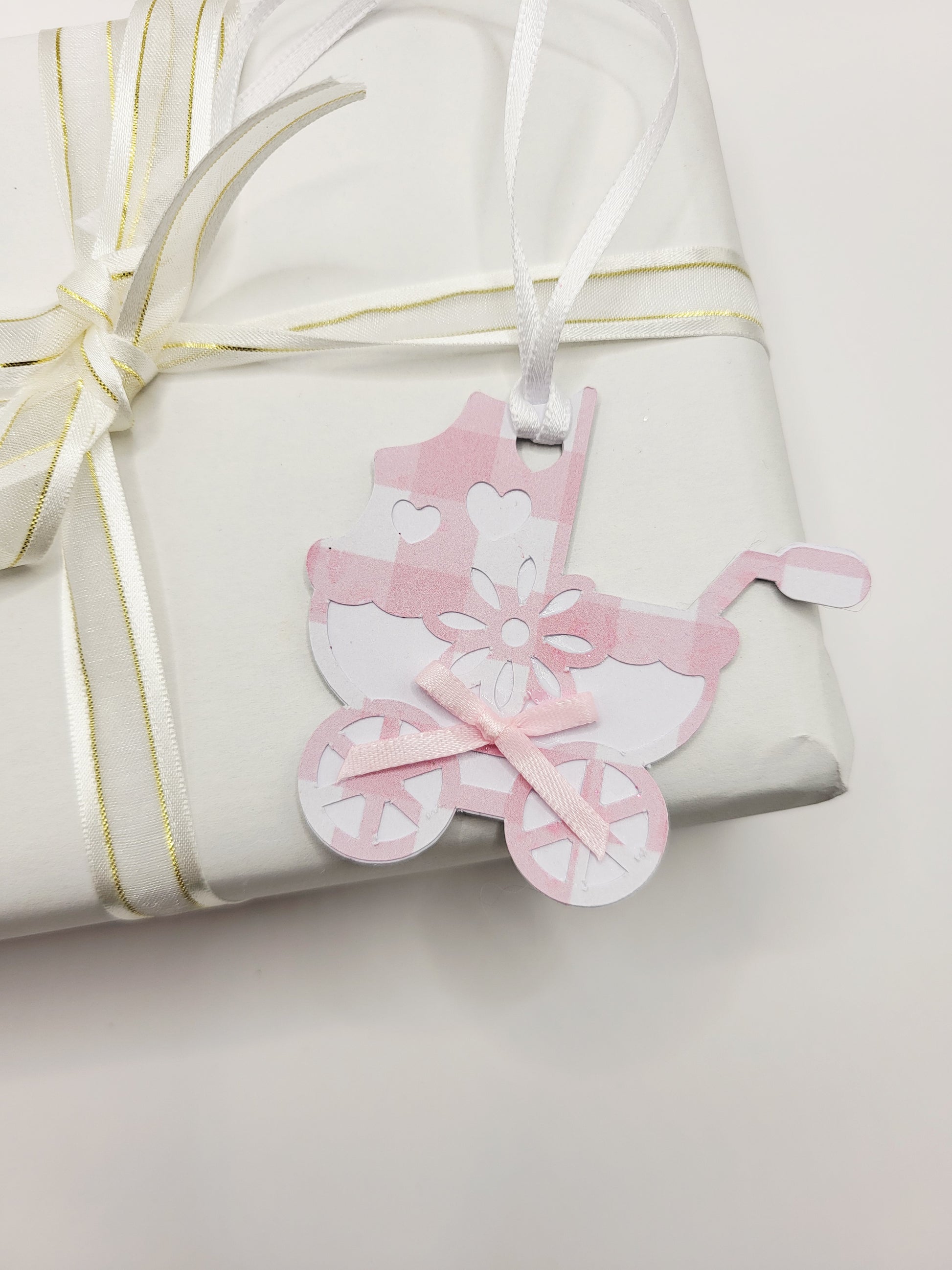 Pink gingham pram shaped gift tag. This tag has a pink bow, and a white satin ribbon to attach to your gift