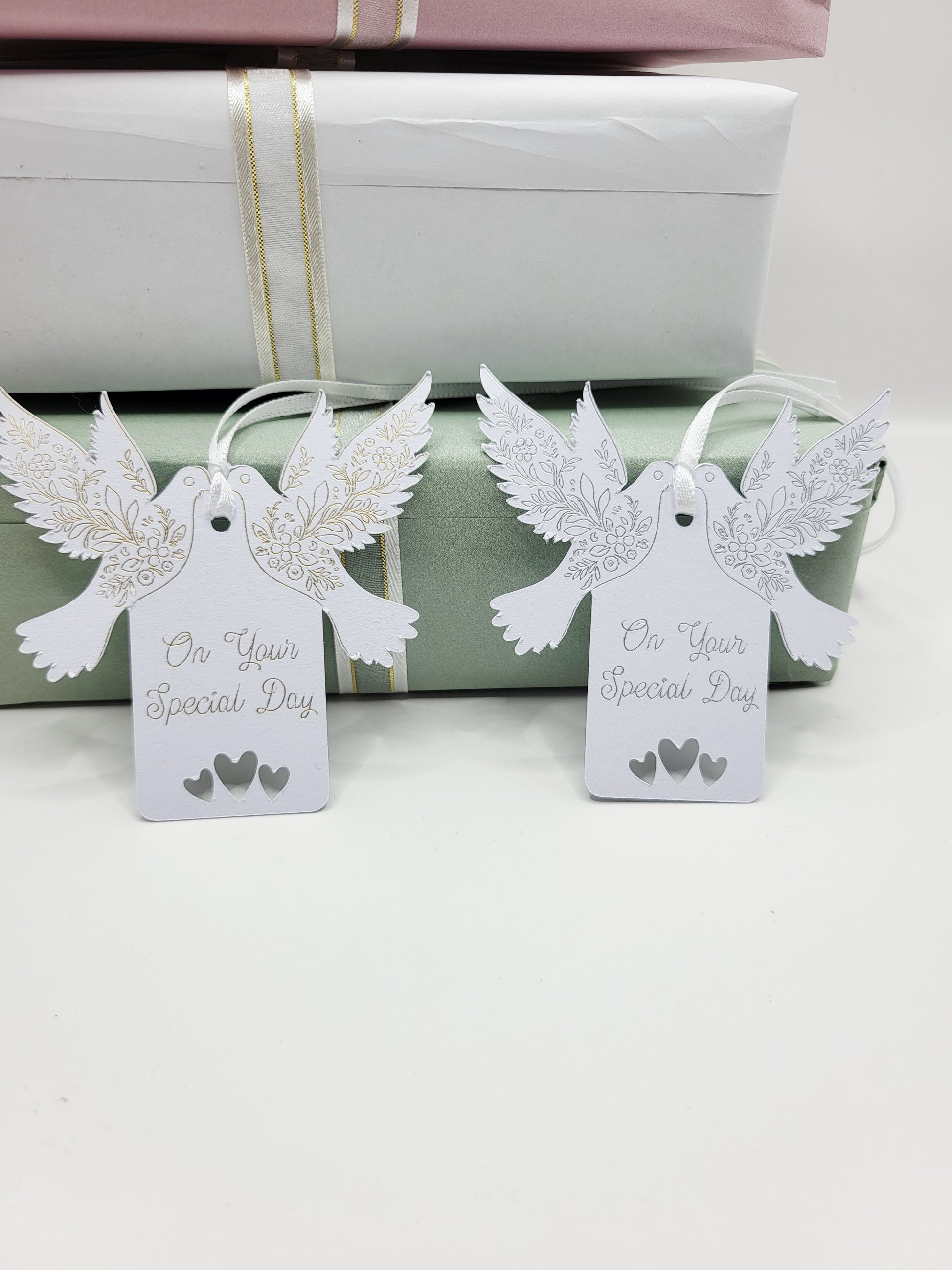 A pair of  white card gift tags with the words On Your Special Day One foiled in silver the other in gold. There are tow doves one each side of the tag near the top. The pattern on the wings are also foiled. There are 3 love hearts cut out at the bottom of the tags and they are blank on the reverse 