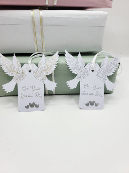 A pair of  white card gift tags with the words On Your Special Day One foiled in silver the other in gold. There are tow doves one each side of the tag near the top. The pattern on the wings are also foiled. There are 3 love hearts cut out at the bottom of the tags and they are blank on the reverse 