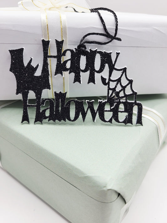 Black glittery 'Happy Halloween' cut out decoration with a spiderweb  and a bat cut out in between Happy and Halloween