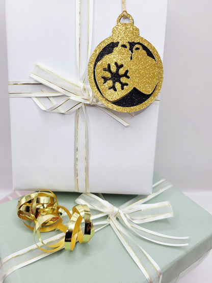 Christmas Bauble shape gift tag has a black glitter background with a gold glitter edge around the bauble and two baubles in gold glitter cardstock in the centre of the bauble. The back is blank and the tag has a gold metallic cord to attach to your gift.