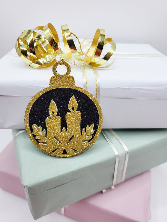 Christmas Bauble shape gift tag has a black glitter background with a gold glitter edge around the bauble and two candles sat on holly in gold glitter cardstock at the bottom of the bauble. The back is blank and the tag has a gold metallic cord to attach to your gift.