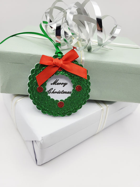 A green glitter Christmas wreath gift tag with a red ribbon bow and 'Merry Christmas' text,
