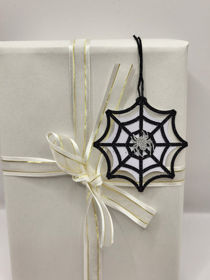 Black glitter spiderweb gift tag with a silver glitter spider stuck in the middle