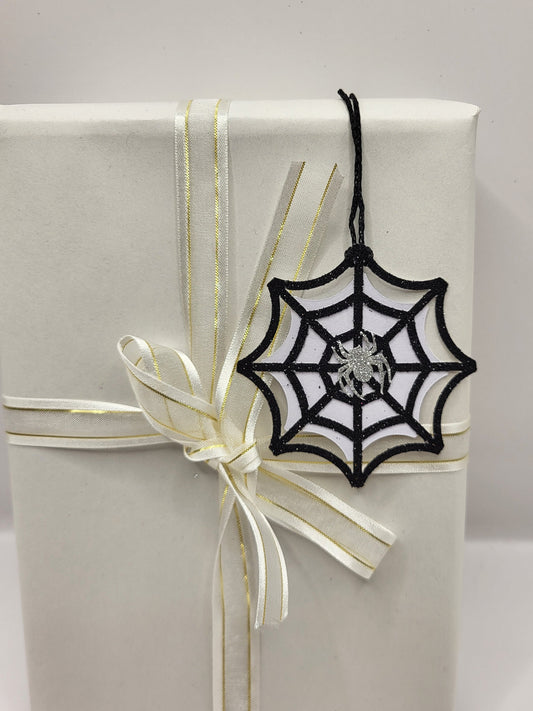 Black glitter spiderweb gift tag with a silver glitter spider stuck in the middle