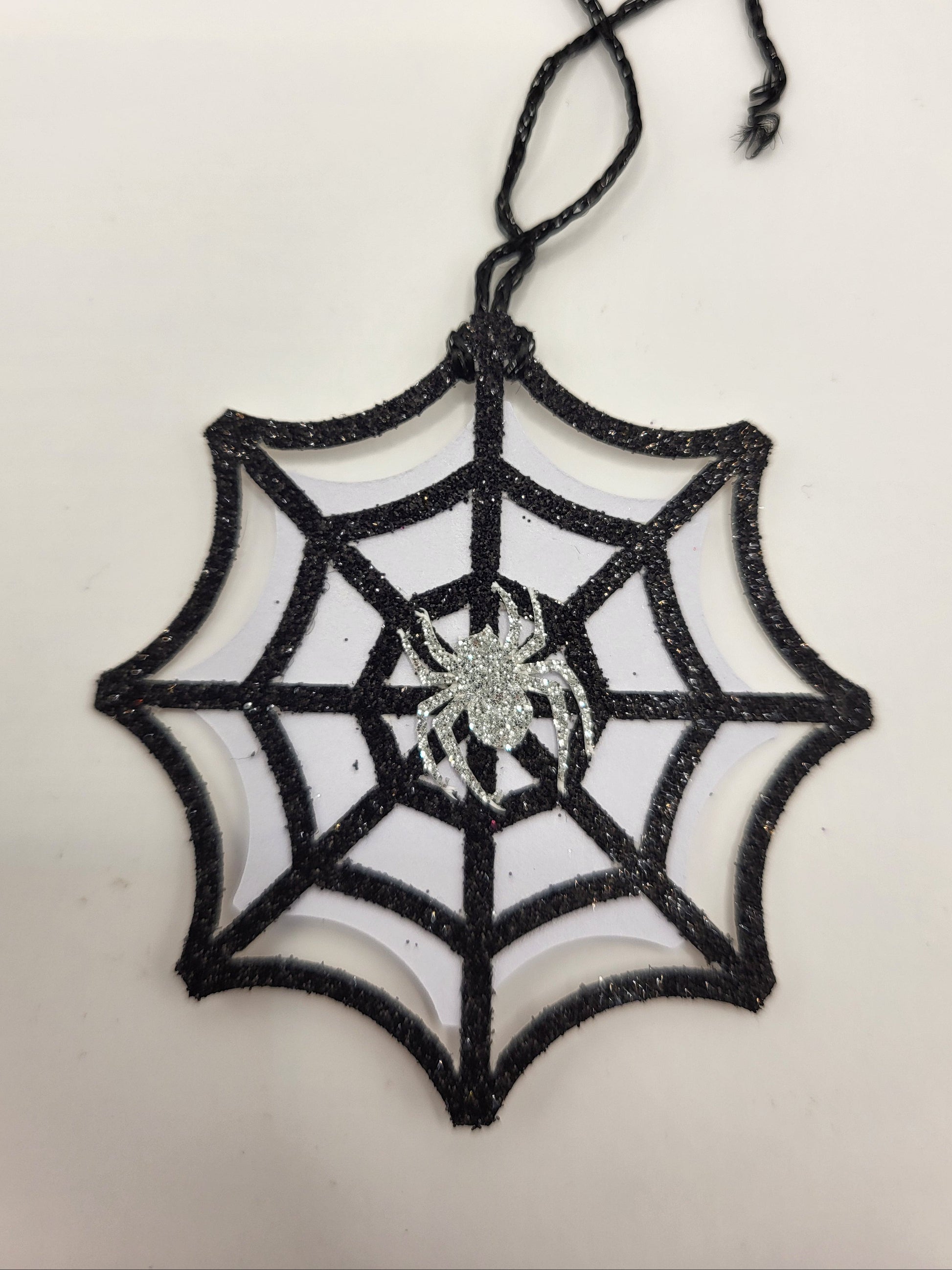 Black glitter spider web decoration with a spider on a white background