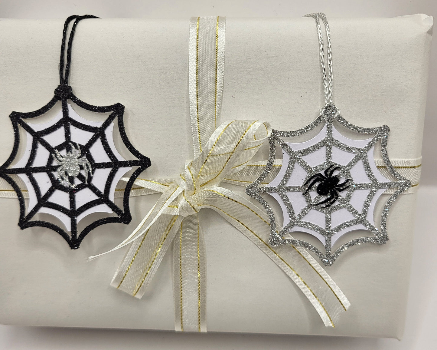 Two glitter spiderweb gift tags. One is black glitter and the other is silver glitter