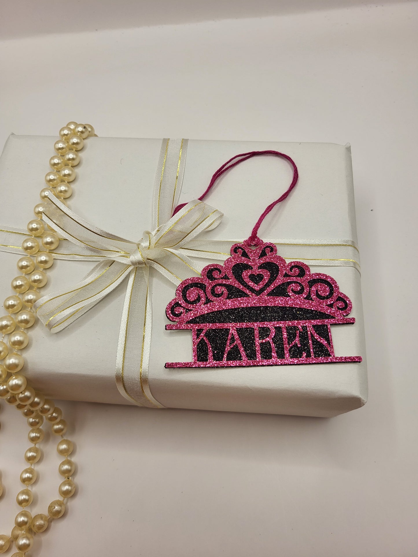 Tiara shaped gift tag is pink glitter card on black glitter card and can be personalised. The tag has a pink silk cord  to enable you to attach to a gift